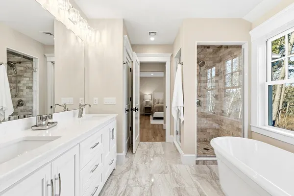 a spacious bathroom with a double vanity sink a mirror and a bathtub