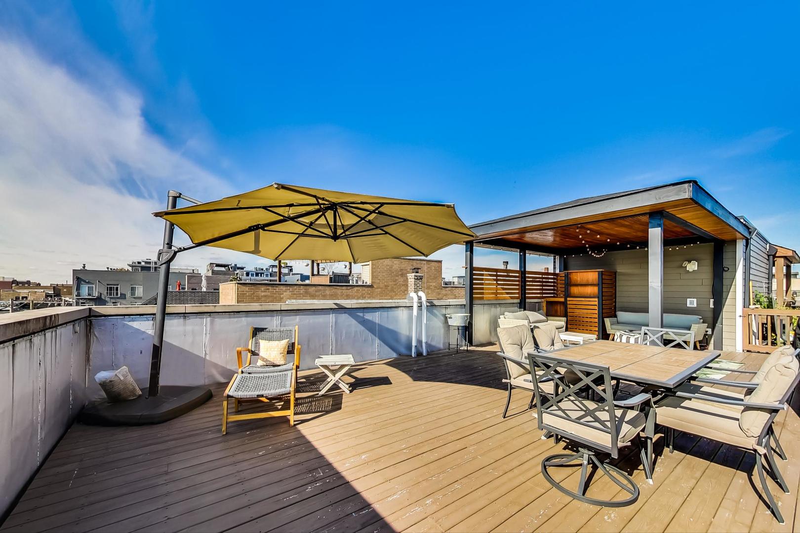 1525 West Fry Street, Unit 2 Chicago, IL 60642 - Photo 26 of 33 a view of a roof deck with table and chairs under an umbrella with wooden floor
