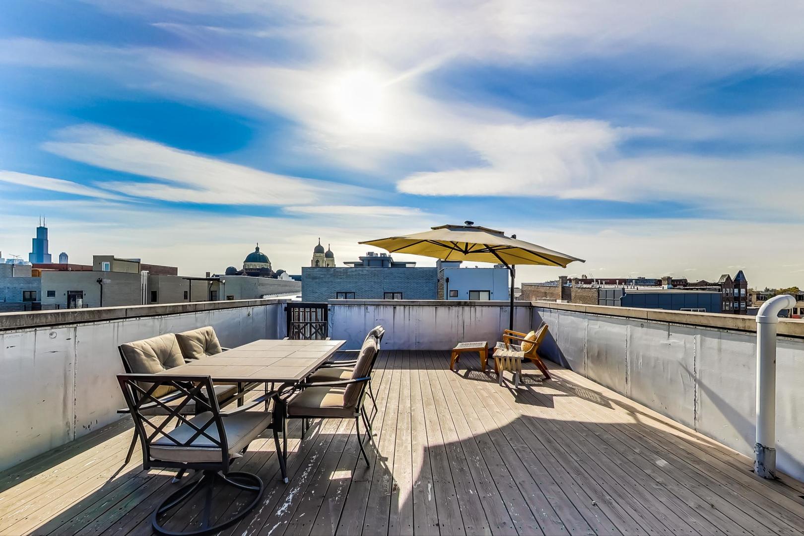 1525 West Fry Street, Unit 2 Chicago, IL 60642 - Photo 28 of 33 a view of a roof deck with dining table and chairs with wooden floor