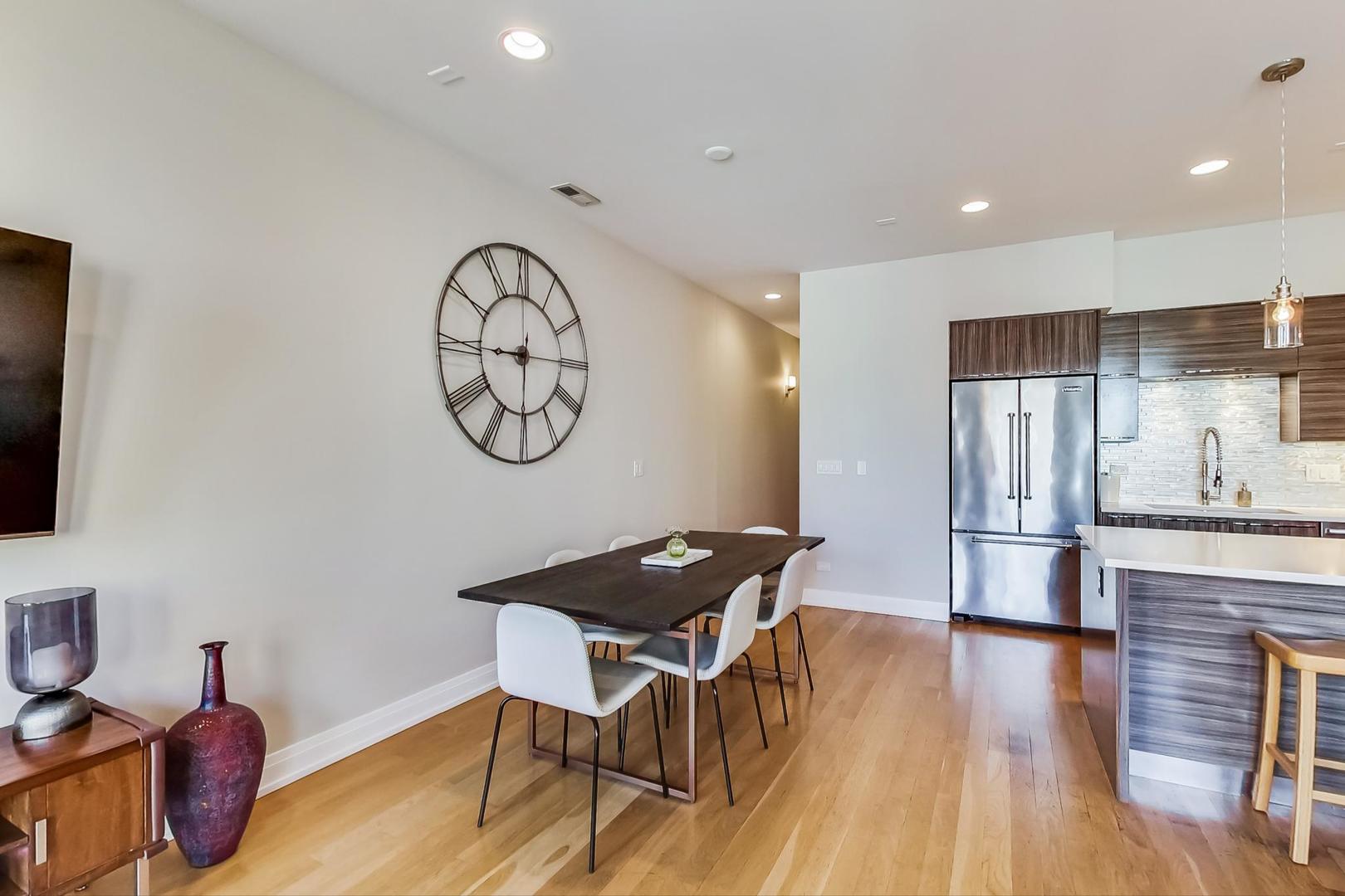 1525 West Fry Street, Unit 2 Chicago, IL 60642 - Photo 7 of 33 a kitchen with granite countertop a table chairs stove a refrigerator and a dining table with wooden floor