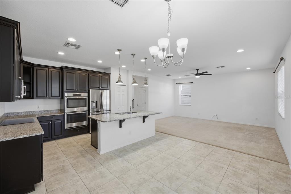 19656 Long Lake Ranch Boulevard Lutz, FL 33558 - Photo 6 of 44 a large white kitchen with a large island oven a sink dishwasher and a fireplace with wooden floor