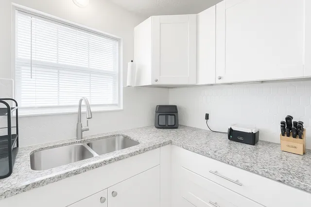 a kitchen with granite countertop white cabinets and a sink