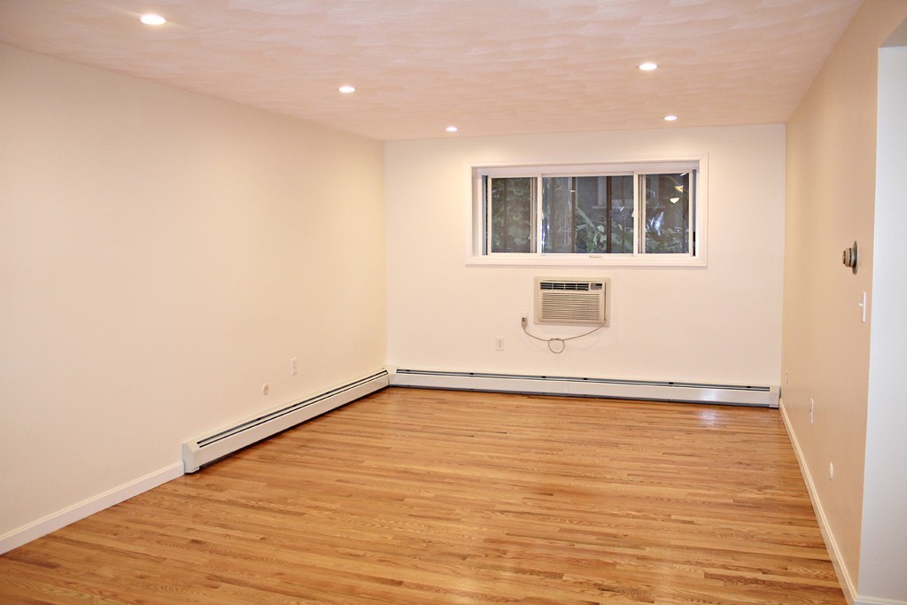 46 Adams Street, Unit A6 Boston, MA 02122 - Photo 4 of 11 a view of an empty room with wooden floor and windows