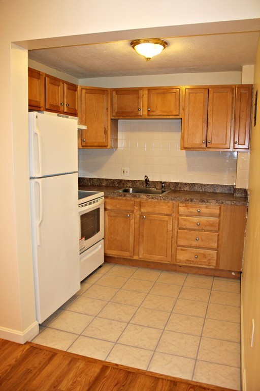 46 Adams Street, Unit A6 Boston, MA 02122 - Photo 6 of 11 a kitchen with stainless steel appliances granite countertop a stove a sink and a refrigerator