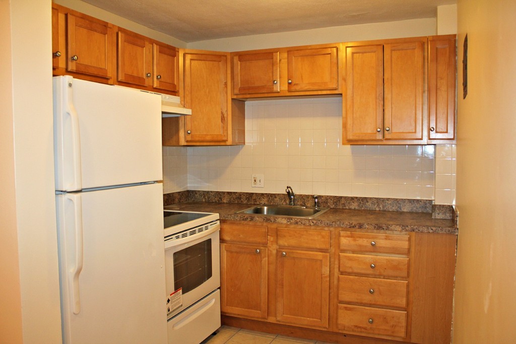 46 Adams Street, Unit A6 Boston, MA 02122 - Photo 7 of 11 a kitchen with granite countertop cabinets stainless steel appliances and a refrigerator