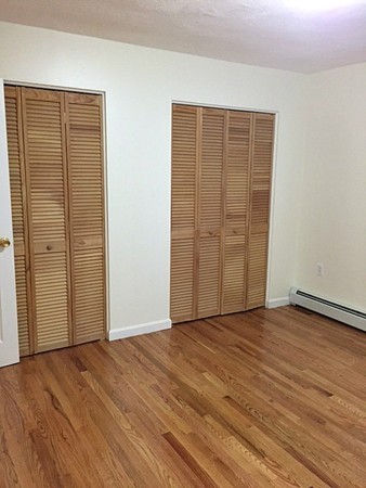 46 Adams Street, Unit A6 Boston, MA 02122 - Photo 10 of 11 an empty room with wooden floor and sliding door