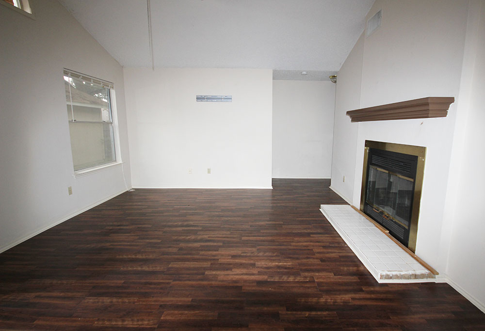 12801 Modena Trail Austin, TX 78729 - Photo 5 of 9 Rich wood-inspired flooring pairs beautifully with a classic brick-lined fireplace under vaulted ceilings.