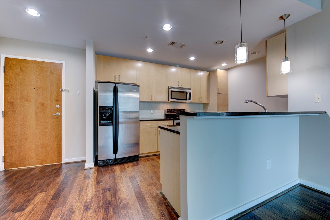 5925 Almeda Road, Unit 2214 Houston, TX 77004 - Photo 2 of 34 a kitchen with a refrigerator a microwave oven a sink and dishwasher with wooden floor