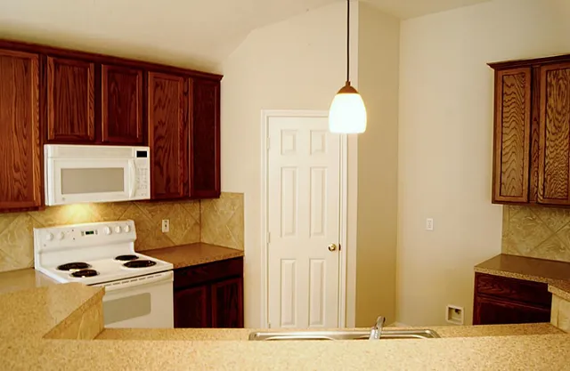 a kitchen with stainless steel appliances granite countertop a stove a sink and a microwave