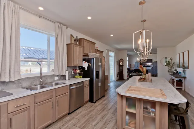 a kitchen with stainless steel appliances a dining table chairs sink and wooden floor