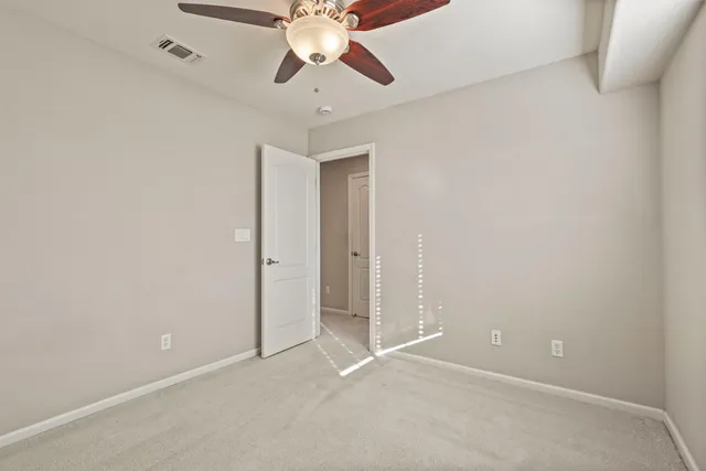 an empty room with a chandelier fan and a ceiling fan