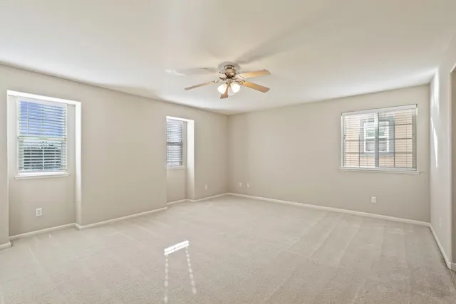an empty room with windows and ceiling fan