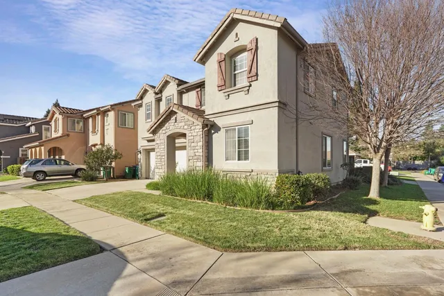 a view of a white house next to a yard with big trees