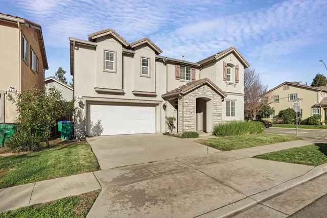a view of a white house with a small yard and plants