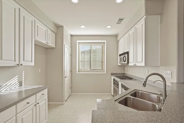 a kitchen with stainless steel appliances granite countertop a sink a stove and a refrigerator with wooden cabinets