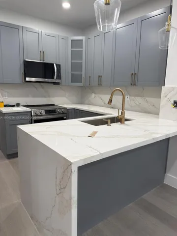 a kitchen with stainless steel appliances a sink a microwave a refrigerator and cabinets