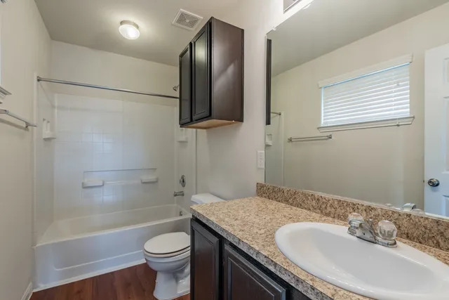 a bathroom with a granite countertop sink toilet and shower