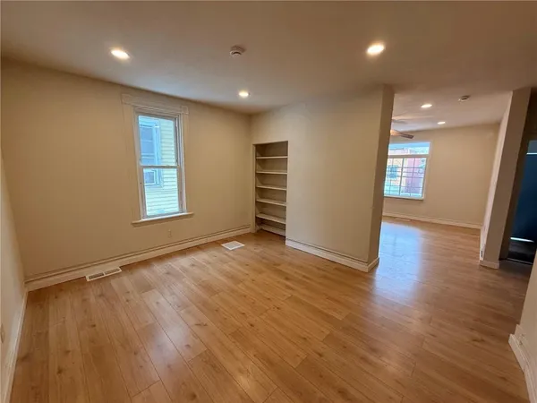 an empty room with wooden floor and windows