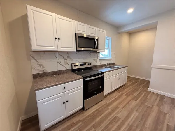 a kitchen with stainless steel appliances granite countertop a stove a sink and a microwave