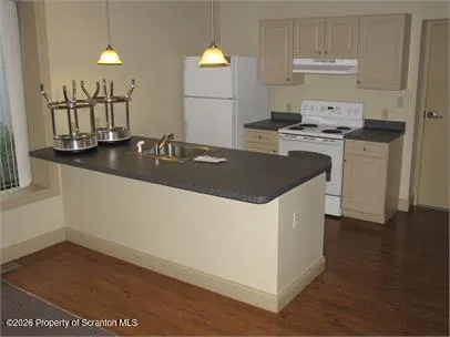 a kitchen with kitchen island granite countertop a sink a stove and wooden floors