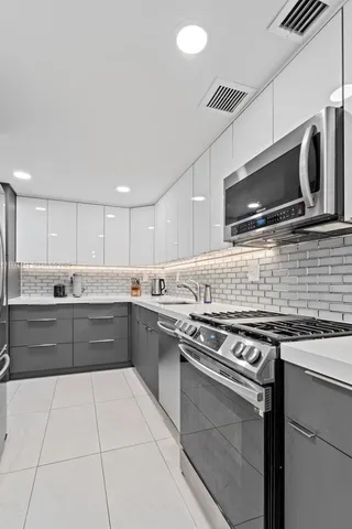 a large kitchen with stainless steel appliances granite countertop a stove and a microwave