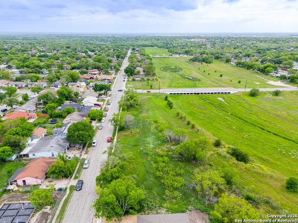an aerial view of residential houses with outdoor space and trees