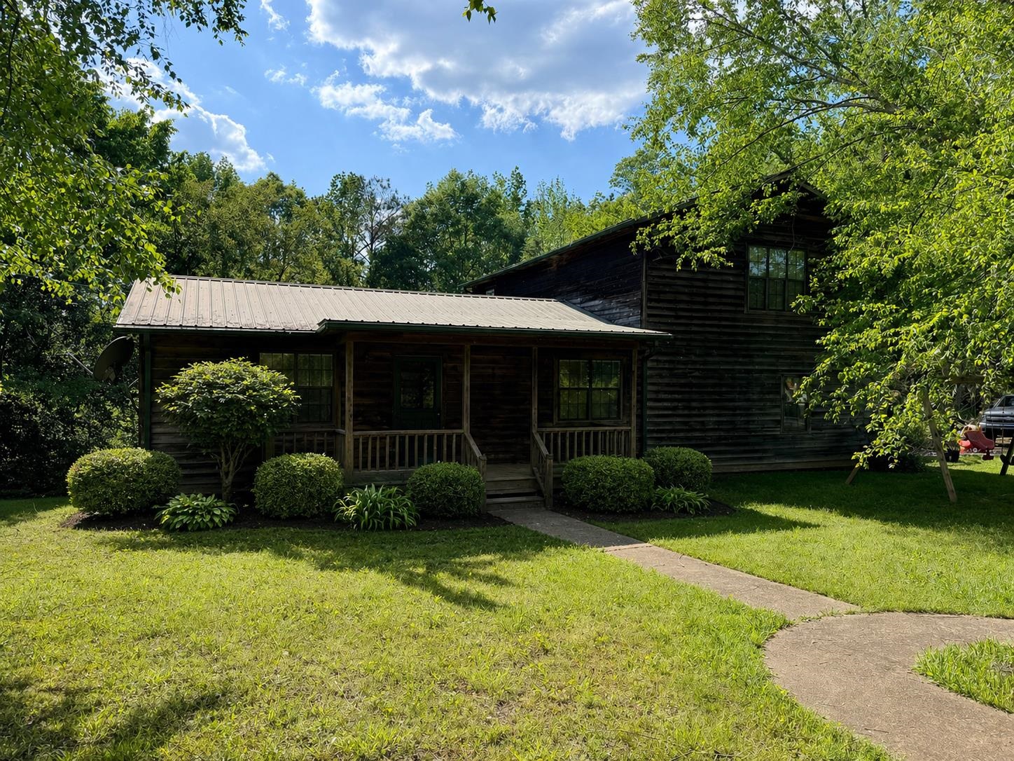 Rustic log cabin exterior featuring a covered front porch with wood railings and a metal roof