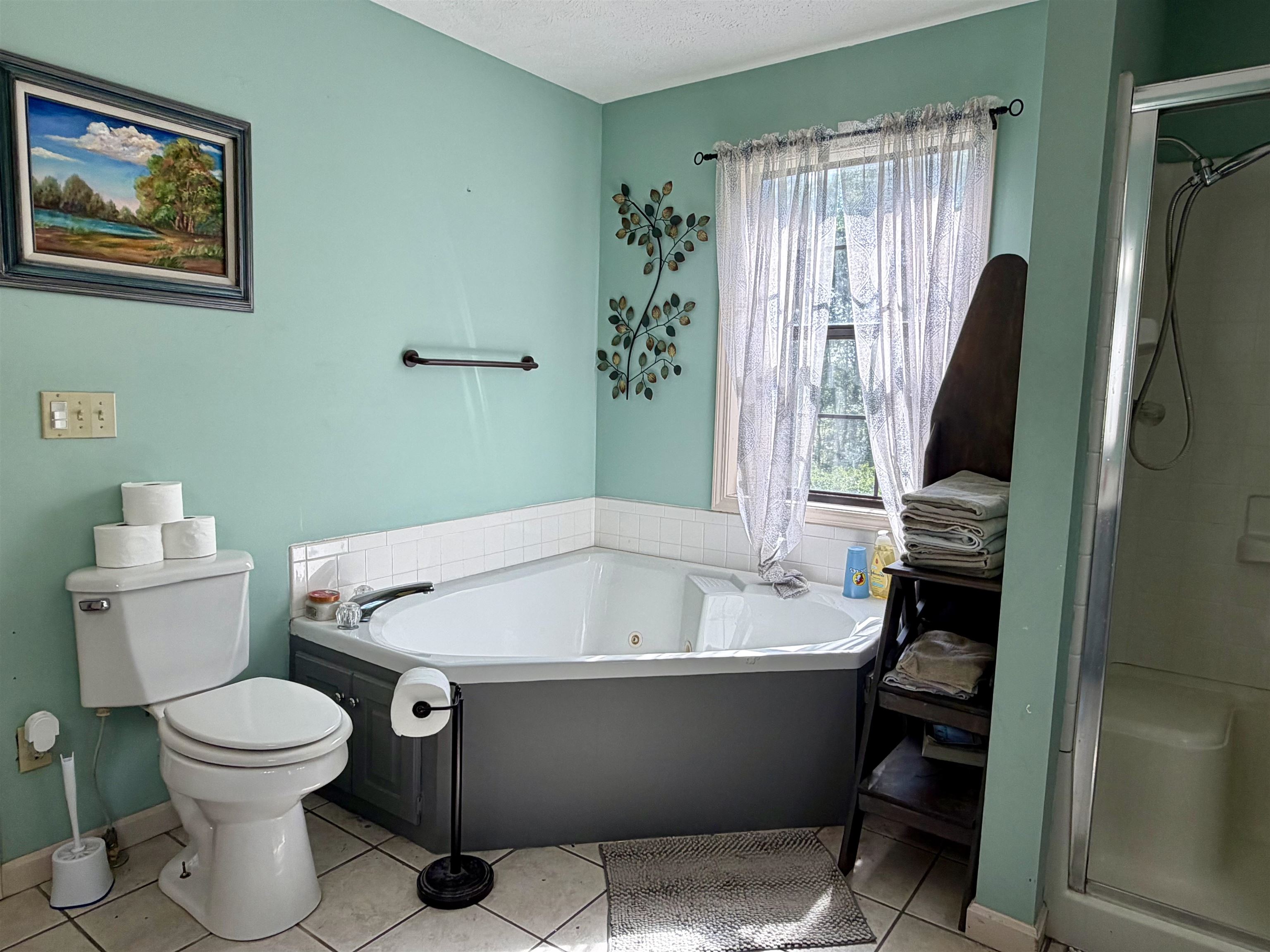 1536 Robinson Shed Road Bethel Springs, TN 38315 - Photo 16 of 23 Corner jetted tub with white tile surround, a single window, and an adjacent shower enclosure