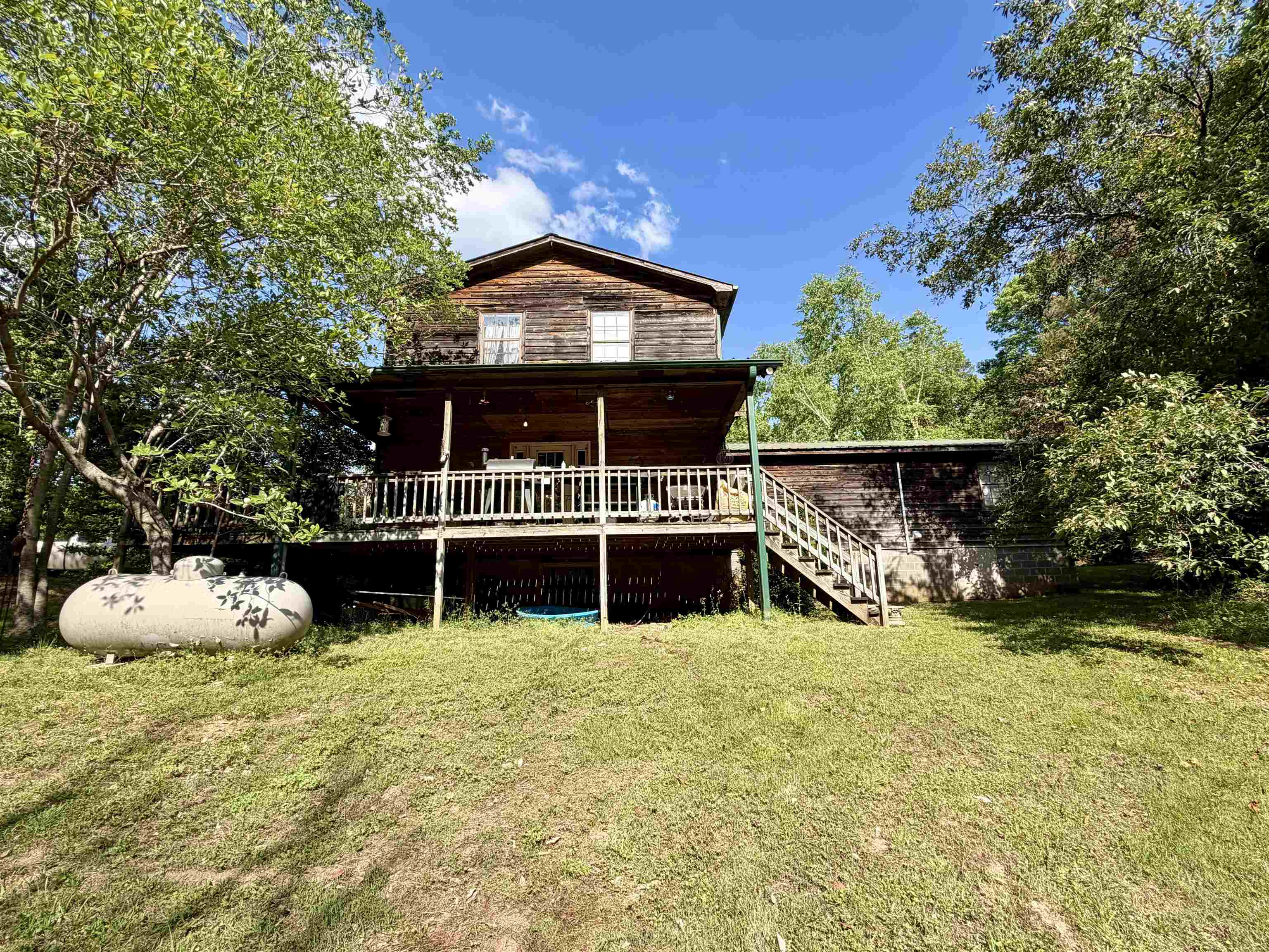1536 Robinson Shed Road Bethel Springs, TN 38315 - Photo 20 of 23 Two-story wood-sided residence featuring a covered upper deck with white railing, exterior staircase, and ground-level patio