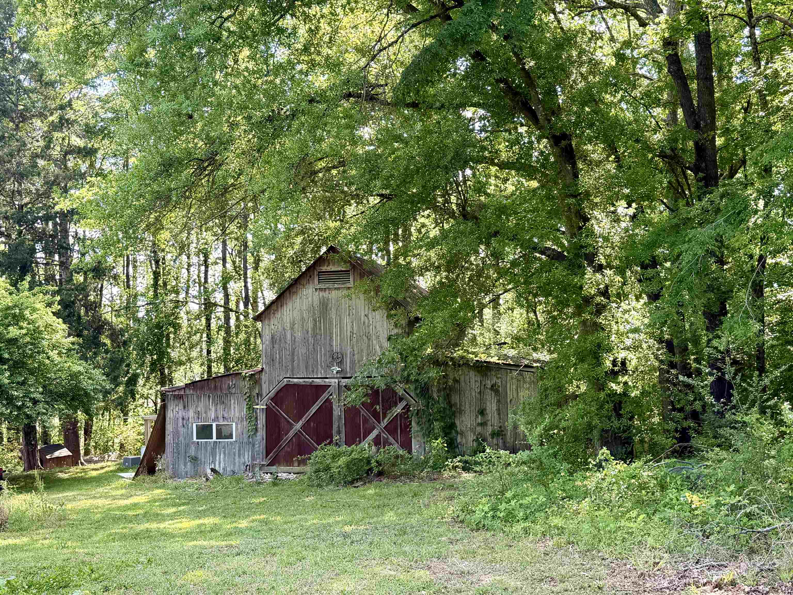 1536 Robinson Shed Road Bethel Springs, TN 38315 - Photo 22 of 23 Rustic wooden barn structure featuring red barn doors and a side window