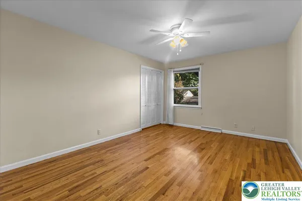 a view of an empty room with window and chandelier fan