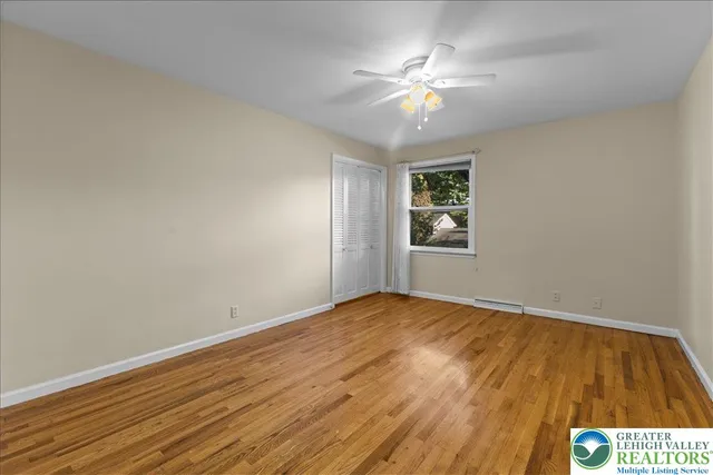a view of an empty room with window and chandelier fan