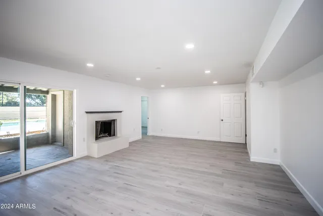 an empty room with wooden floor and fireplace