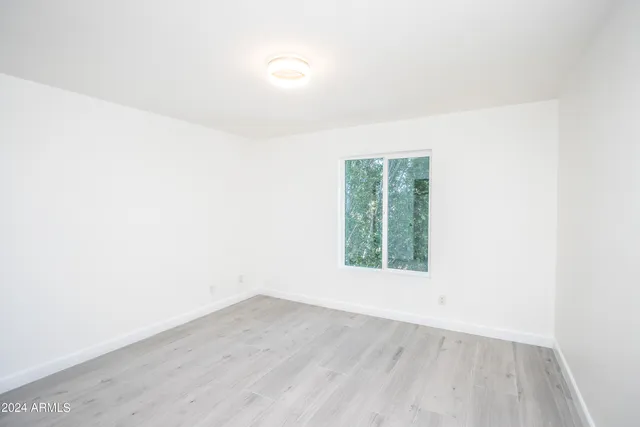 an empty room with wooden floor and window