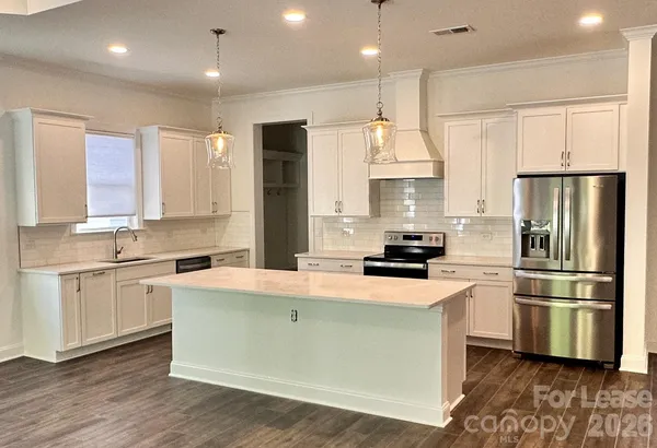 a kitchen with kitchen island white cabinets a refrigerator and a stove