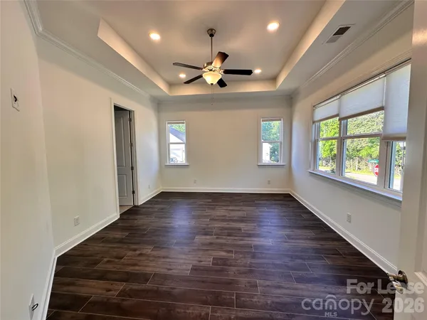 an empty room with wooden floor chandelier and windows