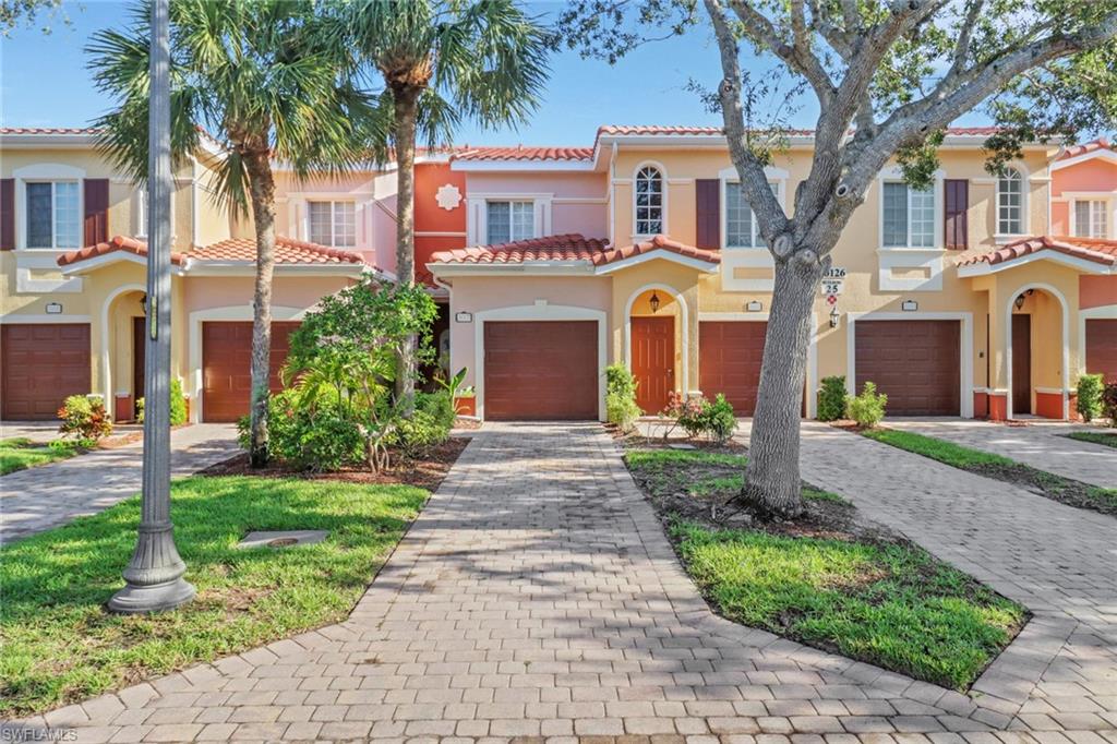 10126 Villagio Palms Way, Unit 107 Estero, FL 33928 - Photo 1 of 43 a front view of a house with yard and green space