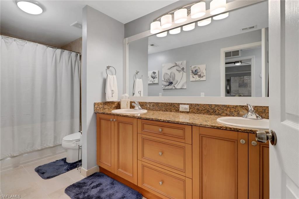10126 Villagio Palms Way, Unit 107 Estero, FL 33928 - Photo 20 of 43 a spacious bathroom with a granite countertop sink and a mirror