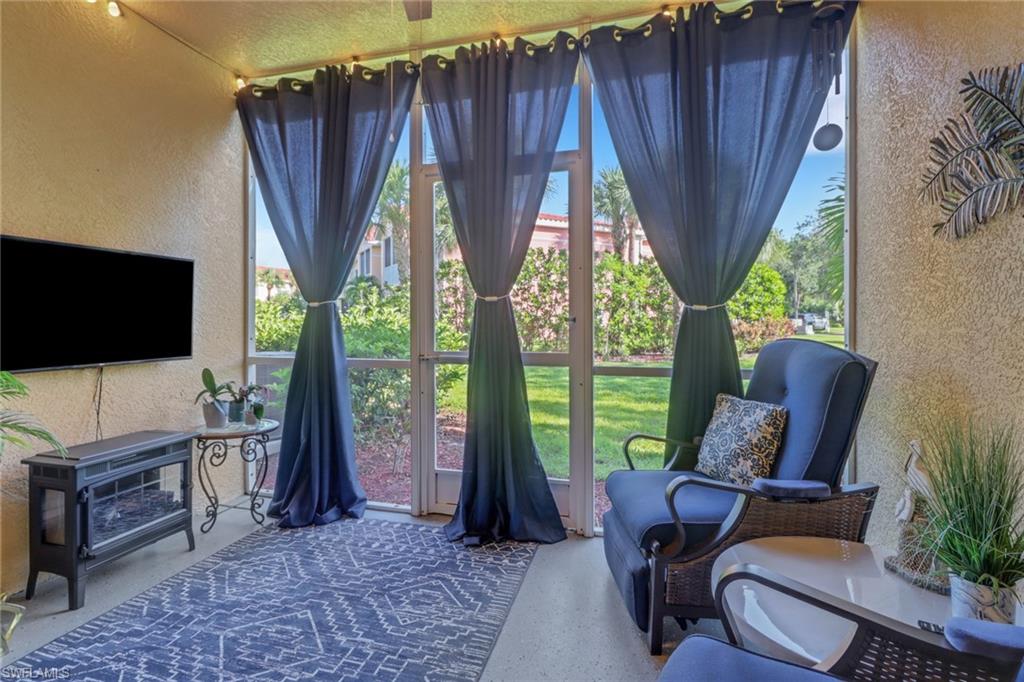 10126 Villagio Palms Way, Unit 107 Estero, FL 33928 - Photo 23 of 43 a living room with furniture a flat screen tv and a floor to ceiling window