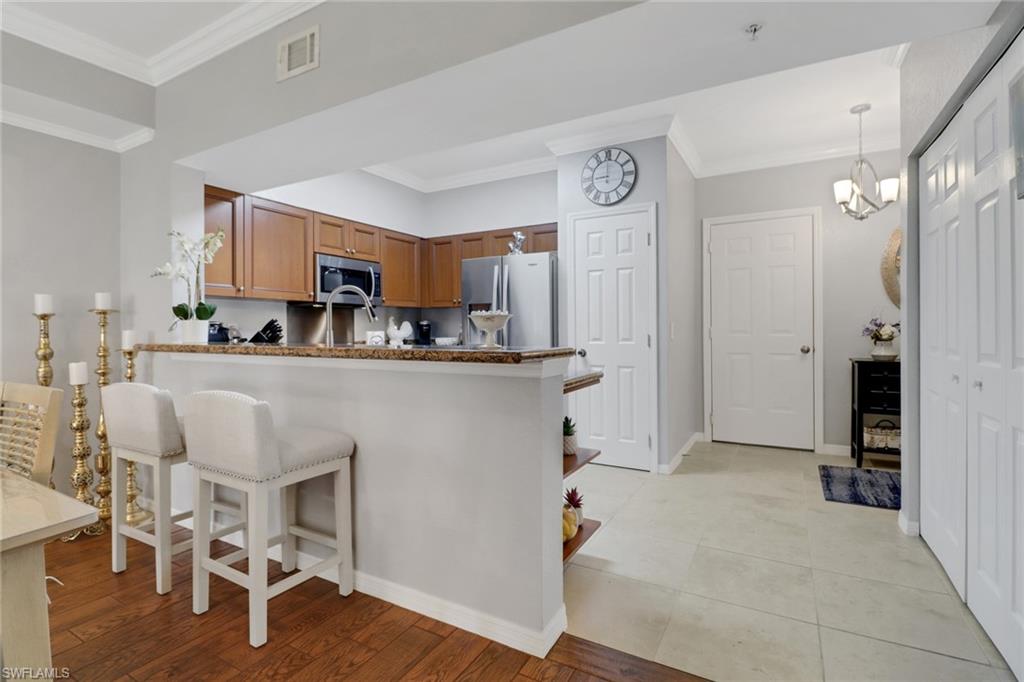 10126 Villagio Palms Way, Unit 107 Estero, FL 33928 - Photo 6 of 43 a kitchen with stainless steel appliances kitchen island granite countertop a refrigerator and a stove top oven