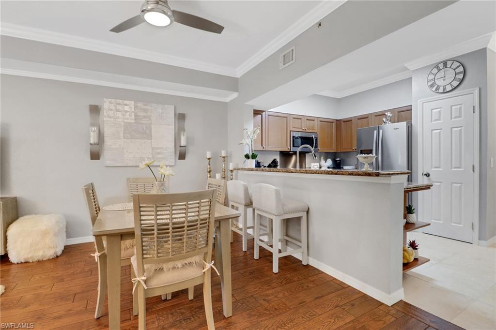 10126 Villagio Palms Way, Unit 107 Estero, FL 33928 - Photo 7 of 43 a kitchen with kitchen island a dining table chairs and a refrigerator