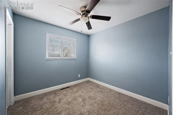an empty room with a window and a ceiling fan