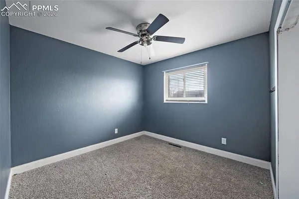 an empty room with a window and a fan
