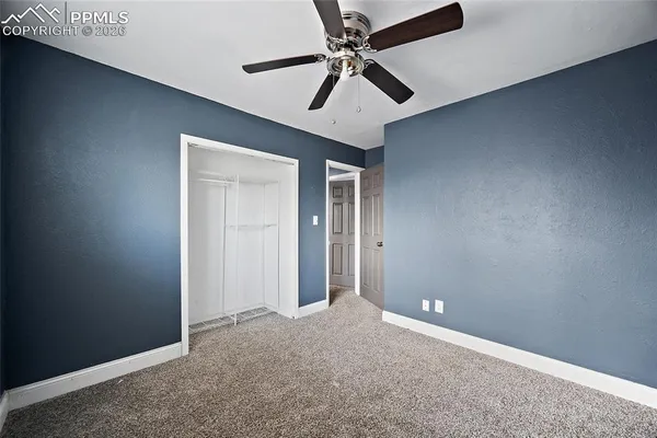 an empty room with closet and a ceiling fan