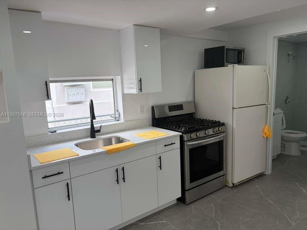 1011 Southwest 5th Street, Unit 1 Miami, FL 33130 - Photo 9 of 12 a kitchen with a sink and a stove top oven