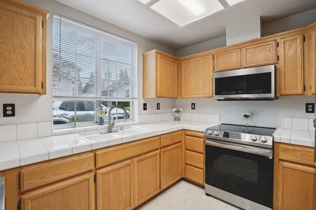 a kitchen with stainless steel appliances granite countertop a sink a stove a microwave and wooden cabinets