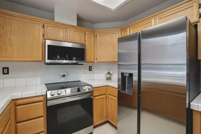 a kitchen with stainless steel appliances granite countertop a refrigerator a stove top oven a sink and dishwasher