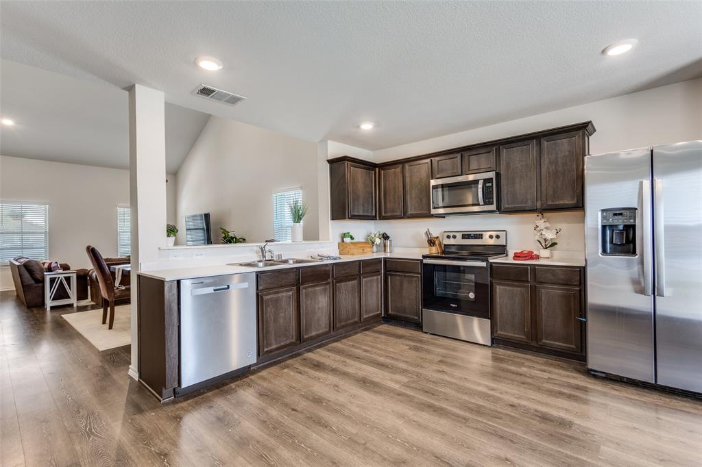 305 Ginger Avenue Anna, TX 75409 - Photo 8 of 28 a kitchen with stainless steel appliances kitchen island granite countertop a refrigerator a sink dishwasher a stove with wooden cabinets and floor