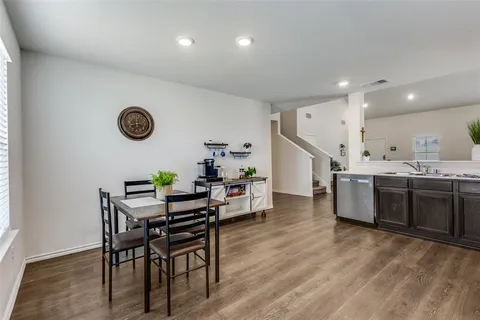 a living room with kitchen island furniture wooden floor and clock on the wall