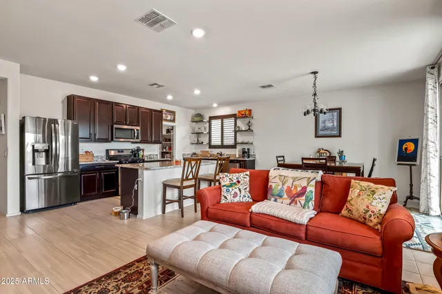 a living room with stainless steel appliances furniture and a kitchen view